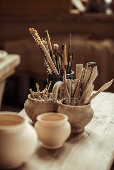 Primo piano di pennelli con strumenti di ceramica in ciotole sul tavolo — Foto stock