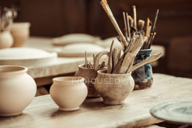 Close up de pincéis de tinta com ferramentas de cerâmica em tigelas na mesa — Fotografia de Stock