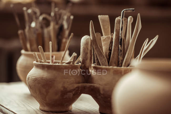 Close up de pincéis de tinta com ferramentas de cerâmica em tigelas na mesa — Fotografia de Stock