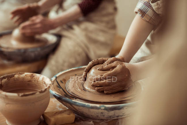 Primo piano delle mani dei bambini che lavorano sulla ruota della ceramica in officina — Foto stock