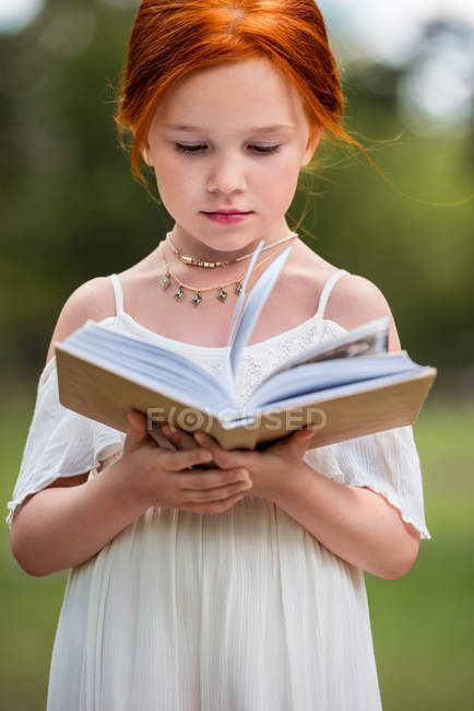 Fille lecture livre dans le parc — Photo de stock