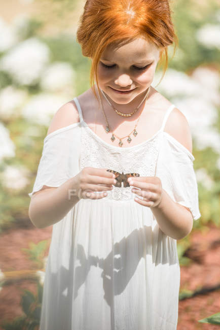 Niña sosteniendo mariposa - foto de stock