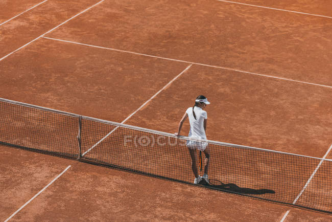Aus der Vogelperspektive: Frau entspannt sich auf Tennisplatz und lehnt sich am Netz zurück — Stockfoto