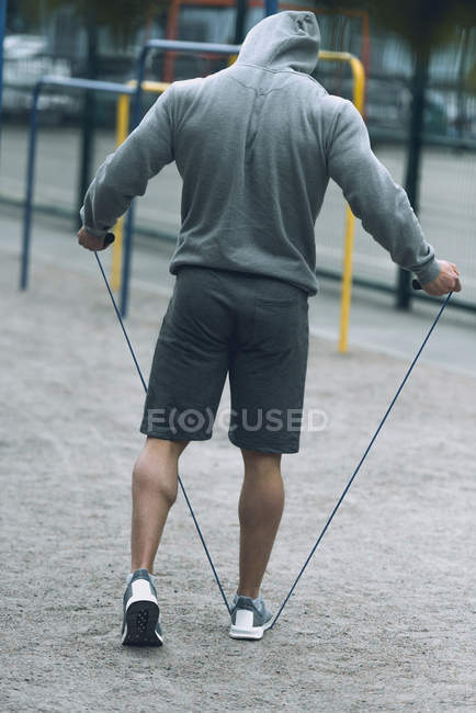 Vista trasera del deportista saltando la cuerda en el campo de deportes - foto de stock