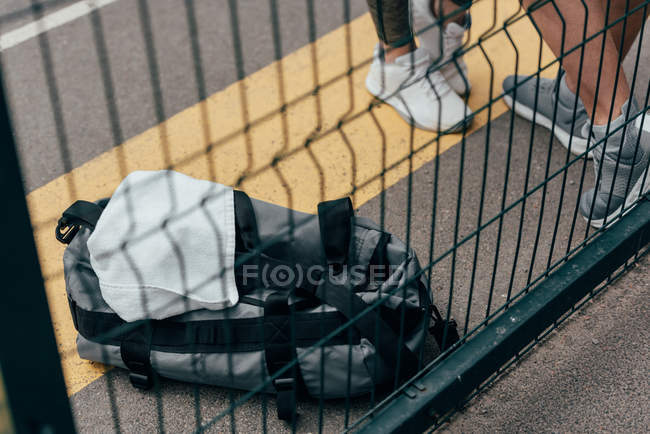 Imagem cortada de desportista e desportista em pé perto de cerca em terreno desportivo — Fotografia de Stock