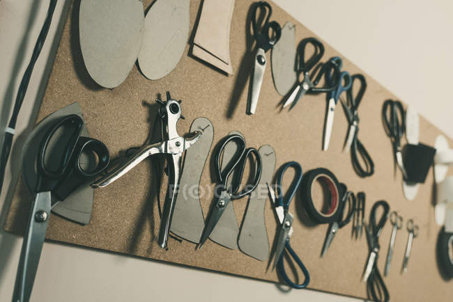 Various scissors hanging on board at shoemaker workshop — Stock Photo
