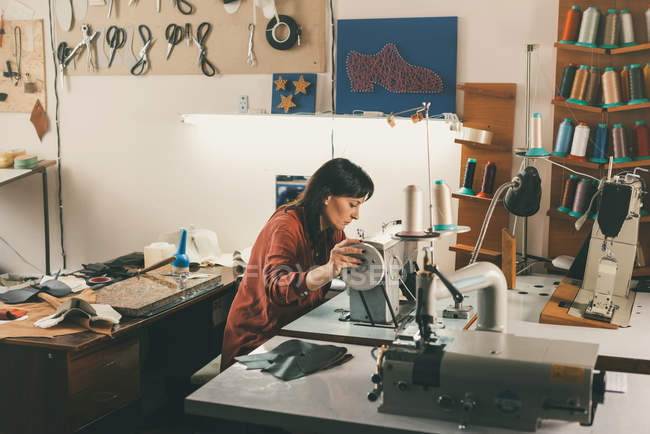 Costurera que trabaja con la máquina de coser eléctrica en sastrería - foto de stock