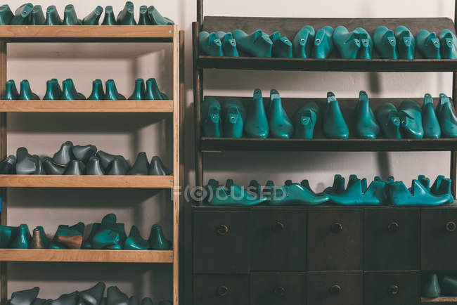 Plastic footwear workpieces on shelves at cobbler shop — Stock Photo
