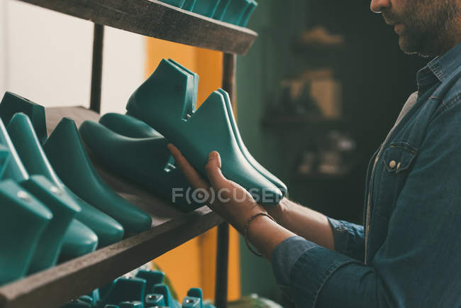 Cropped shot of bearded shoemaker holding footwear workpieces — Stock Photo