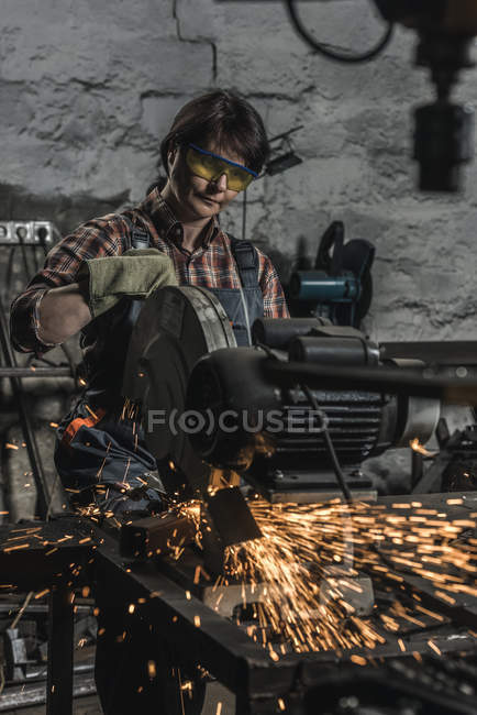 Female welder in protective googles using welding torch in workshop — Stock Photo