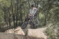 Rennfahrer springt mit Mountainbike in Wald — Stockfoto