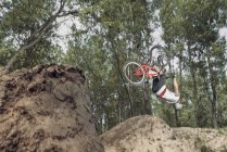 Racer performing flip over with bike in forest — Stock Photo