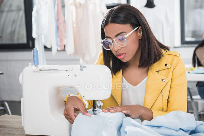 Joven costurera que trabaja con la máquina de coser - foto de stock