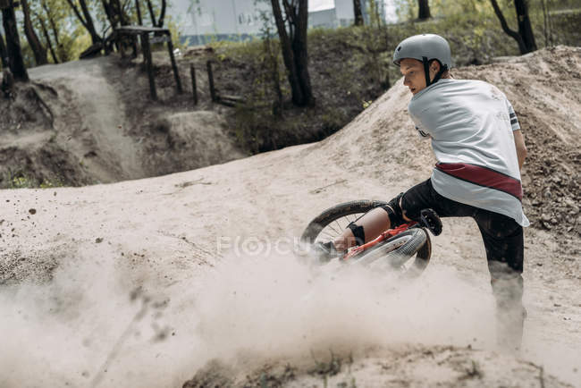 Dust after racer in helmet riding bike — Stock Photo