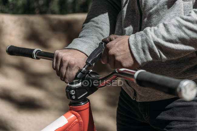 Cropped image of racer fixing bicycle on nature — Stock Photo